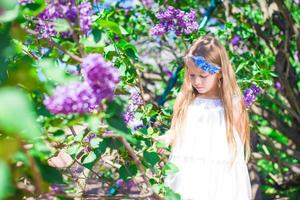 Adorable happy little girl in flower blossoming garden photo