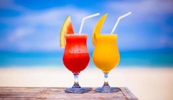 Two tasty fruits cocktails on background of turquoise sea photo