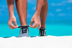 joven corredor masculino preparándose para comenzar en la playa blanca foto