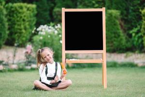 Happy little schoolgirl with a chalkboard outdoor photo