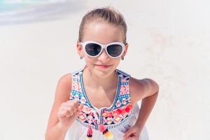 Adorable active little girl at beach during summer vacation photo