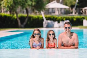familia feliz de cuatro en la piscina al aire libre foto