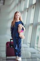 adorable niña en el aeropuerto con su equipaje esperando el embarque foto