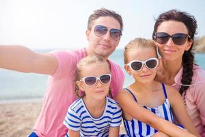 joven y hermosa familia tomando selfie en la playa foto