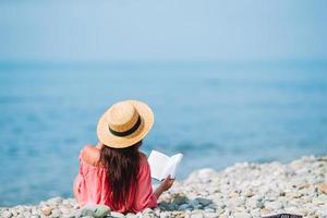 mujer joven leyendo un libro durante la playa blanca tropical foto