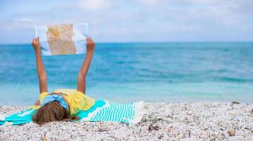 Adorable little girl with map of island on tropical beach photo