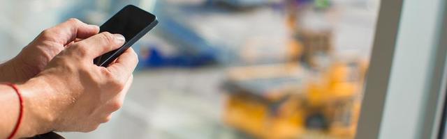 Close up man's hands using cellphone inside airport photo