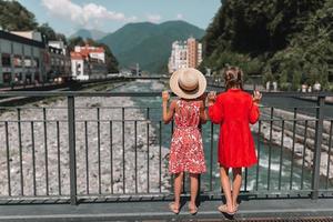 Back view of girls on the embankment of a mountain river in a European city. photo