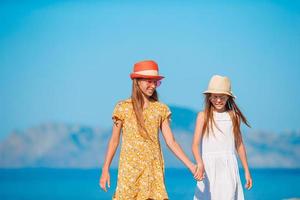 Little happy funny girls have a lot of fun at tropical beach playing together photo