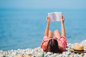 Young woman reading book during tropical white beach photo