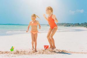 Little happy funny girls have a lot of fun at tropical beach playing together. photo