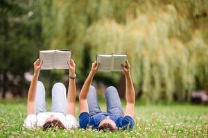 pareja joven relajada leyendo libros mientras está acostado en la hierba foto