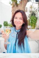 Woman taking selfie sitting in outdoor cafe. photo