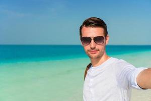 Happy man taking selfie on tropical beach photo