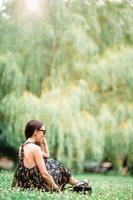 Cute woman is reading text message on mobile phone while sitting in the park. photo