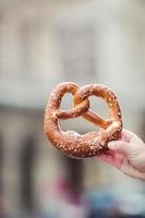 Salted pretzel in the hands of a man on background of the Vienna Opera photo