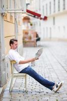 hombre turista con un mapa de la ciudad y una mochila en la calle europa. niño caucásico mirando con mapa de ciudad europea. foto