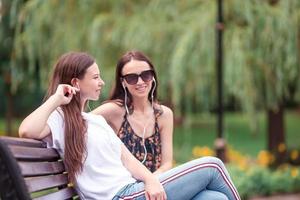 mejores amigos sentados en un banco en un parque de verano foto