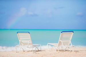 tumbonas blancas en una hermosa playa tropical en maldivas foto