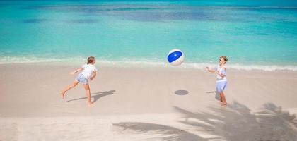 Little adorable girls playing with ball on the beach photo