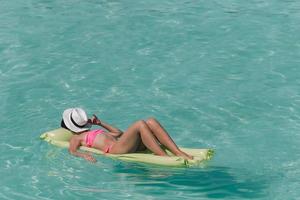 Woman relaxing on inflatable air mattress at turquoise water photo