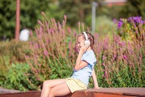 Little adorable girl listening music in the park photo