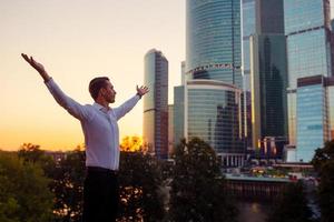 Back view of businessman looking on copy space while standing against glass skyscraper photo