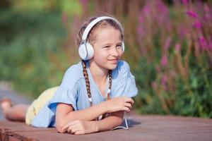 niña adorable escuchando música en el parque foto