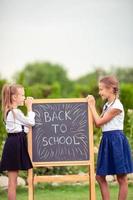 Happy little schoolgirls with a chalkboard outdoor photo