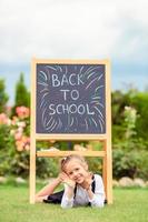 Happy little schoolgirl with a chalkboard outdoor photo