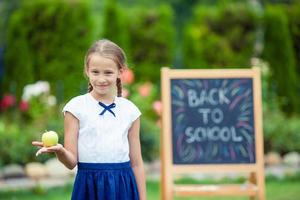 Happy little schoolgirl with a chalkboard outdoor photo