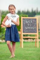 Happy little schoolgirl with a chalkboard outdoor photo