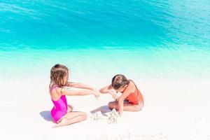 Two kids making sand castle and having fun at tropical beach photo