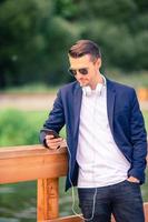 Man is reading text message on mobile phone while walking in the park photo