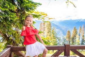 Beautiful happy little girl in mountains in the background of fog photo