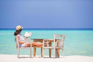 Young woman reading at outdoor beach cafe photo