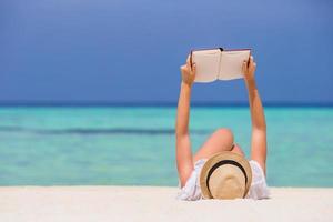 Portrait of a young woman relaxing on the beach, reading a book photo