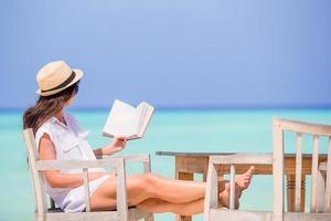 Young woman reading at outdoor beach cafe photo