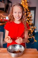 adorable niña horneando galletas de jengibre navideñas foto