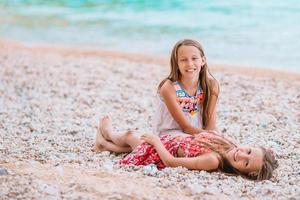 Two little happy girls have a lot of fun at tropical beach playing together photo