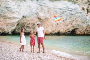 Family flying kite together at tropical white beach photo