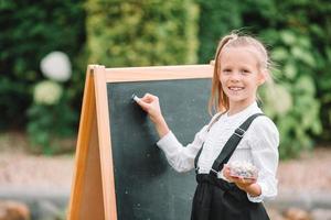 Happy little schoolgirl with a chalkboard outdoor photo