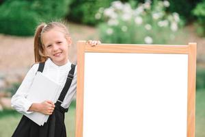 colegiala feliz con una pizarra al aire libre foto