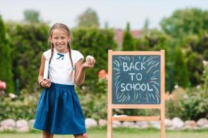 Happy little schoolgirl with a chalkboard outdoor photo