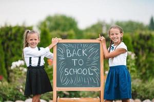 Happy little schoolgirls with a chalkboard outdoor photo