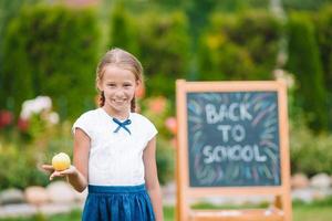 Happy little schoolgirl with a chalkboard outdoor photo