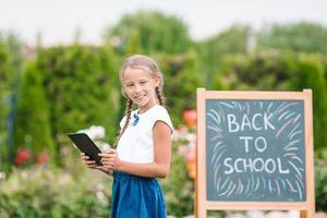 Happy little schoolgirl with a chalkboard outdoor photo