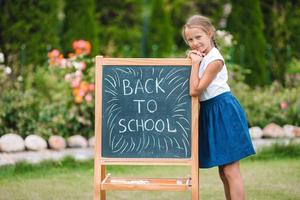 Happy little schoolgirl with a chalkboard outdoor photo