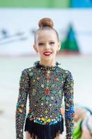 Beautiful little active gymnast girl with her performance on the carpet photo