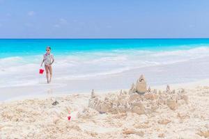 Adorable little girl playing with beach toys on white tropial beach photo